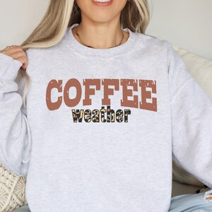 May include: A grey sweatshirt with the text "COFFEE weather" in brown letters with a leopard print design.