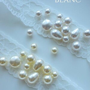 May include: Two rows of white and ivory pearl beads on a white lace background. The top row is labeled "BLANC" and the bottom row is labeled "IVOIRE".
