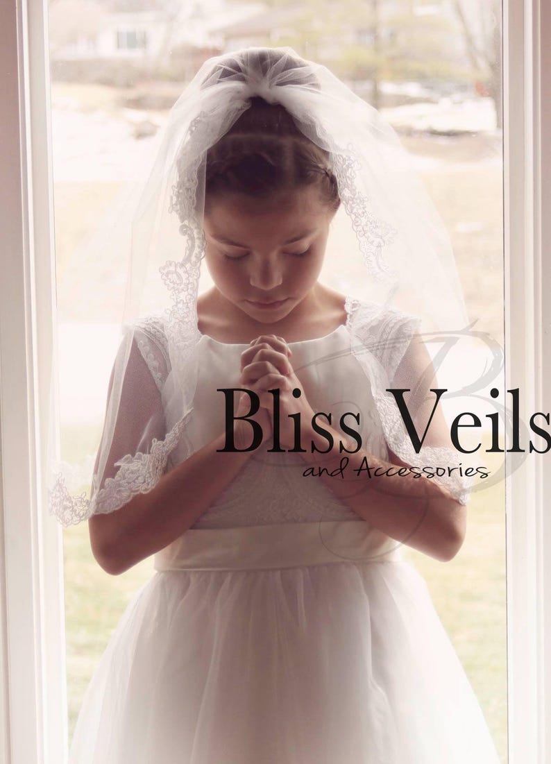 May include: A young girl wearing a white dress and a white lace veil with a white satin sash. She is praying with her hands clasped together. The image has the text "Bliss Veils and Accessories" at the bottom.