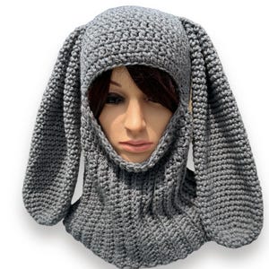 May include: Gray knitted hooded scarf with long bunny ears. The scarf is made of a soft, warm yarn and is perfect for keeping your head and neck warm in the winter.