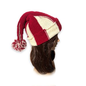 May include: A red and white striped knit hat with a long, pointed tail and a white pom-pom on the end.