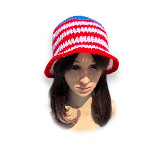 May include: A handmade crochet bucket hat in red, white, and blue stripes. The hat features a blue crown, red brim, and white lining. This patriotic hat is perfect for summer and outdoor events.