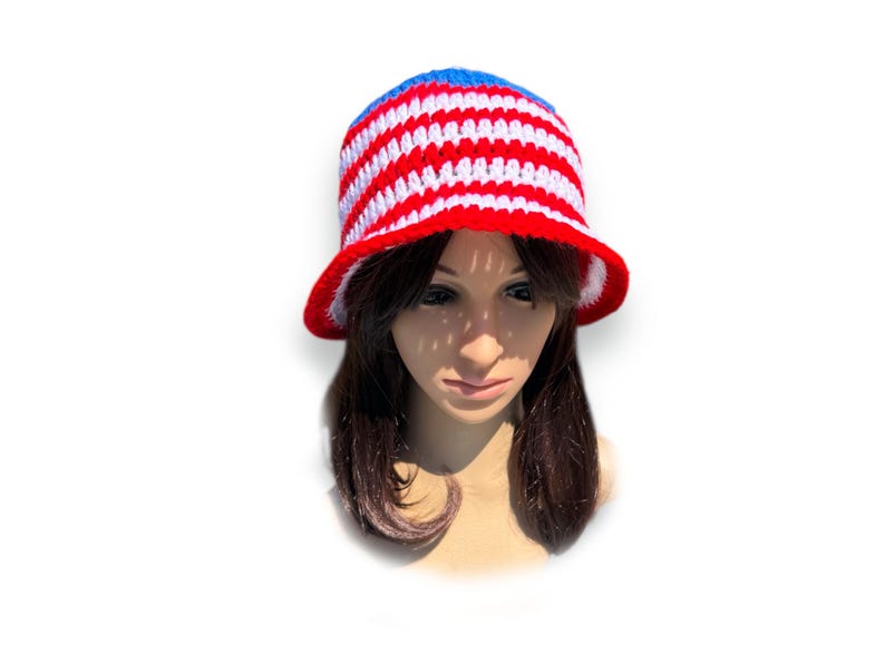 May include: A handmade crochet bucket hat in red, white, and blue stripes. The hat features a blue crown, red brim, and white lining. This patriotic hat is perfect for summer and outdoor events.