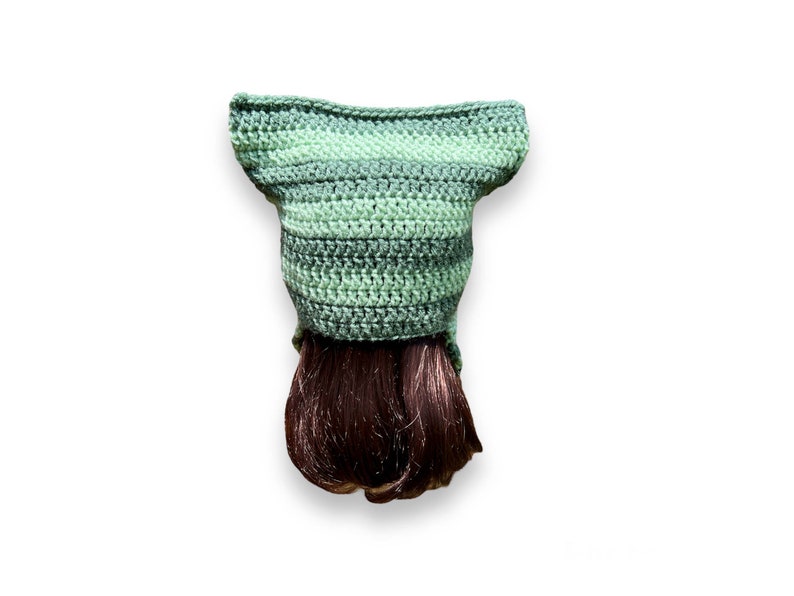 May include: A green and gray crocheted hat with a brown wig attached to the bottom.