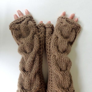 Puede incluir: Un par de guantes sin dedos de punto marr&oacute;n con un patr&oacute;n de trenza.