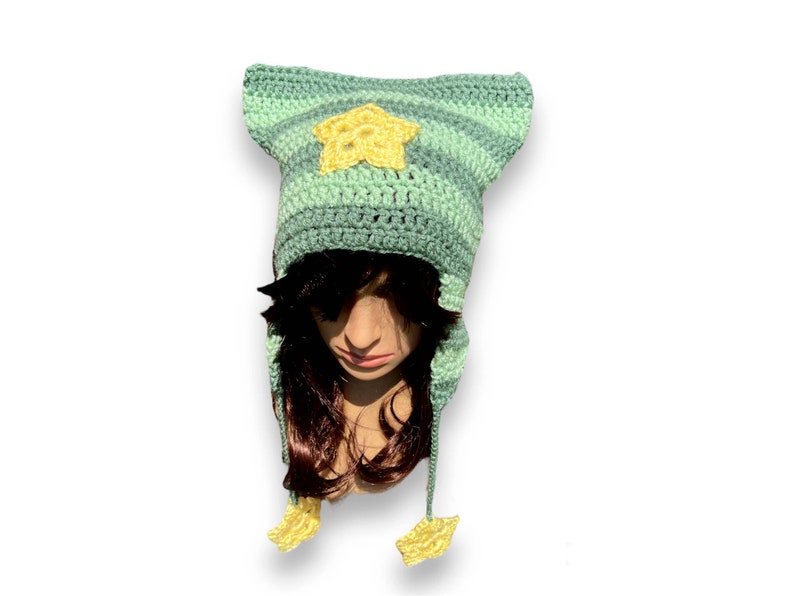 May include: A green and yellow striped crocheted hat with a star on the front and two star-shaped ear flaps.