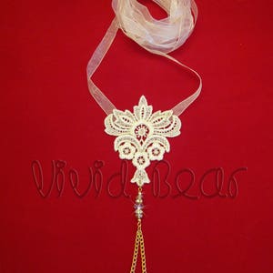May include: White lace foot jewelry with a gold chain and crystal beads. The lace is in a floral design and is attached to a sheer white ribbon.