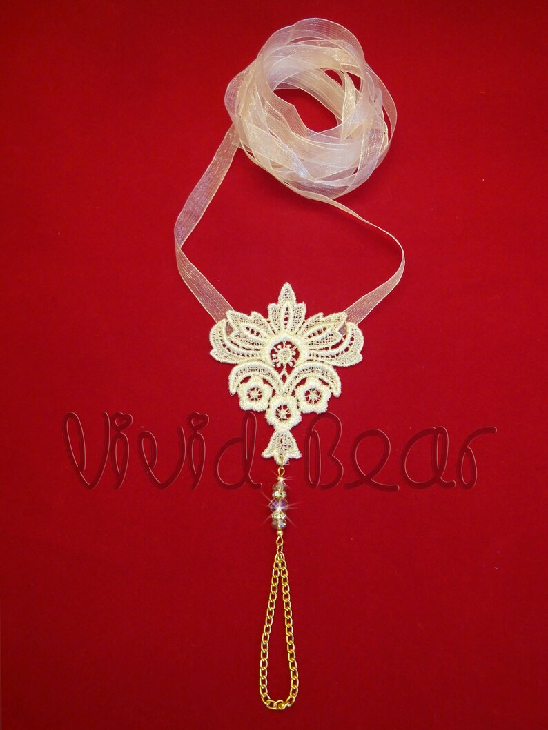 May include: White lace foot jewelry with a gold chain and crystal beads. The lace is in a floral design and is attached to a sheer white ribbon.