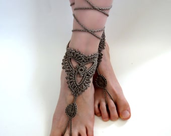 Può includere: Un paio di gioielli per i piedi all'uncinetto con un design delicato. I gioielli per i piedi sono realizzati in filato marrone e hanno un motivo a pizzo. I gioielli sono legati intorno alle caviglie con lunghi lacci.