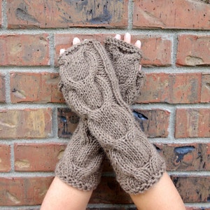 Puede incluir: Un par de guantes sin dedos de punto marr&oacute;n con un patr&oacute;n de trenza.