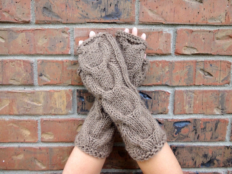 Puede incluir: Un par de guantes sin dedos de punto marr&oacute;n con un patr&oacute;n de trenza.