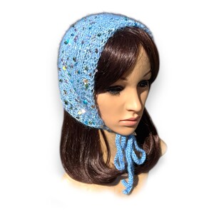 May include: A light blue knitted hat with sequins and a matching tie. The hat is worn on a mannequin with long brown hair.
