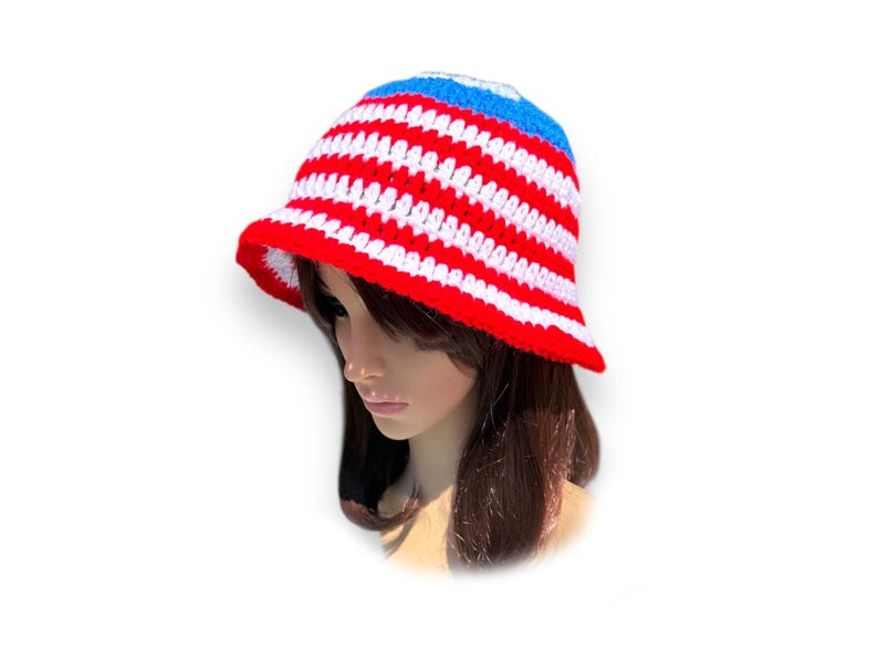 May include: A red, white, and blue crochet bucket hat. The hat features horizontal stripes of red and white, with a blue band at the top. The brim is red. This handmade hat is a stylish accessory.
