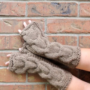Puede incluir: Un par de guantes sin dedos de punto marr&oacute;n con un patr&oacute;n de trenza.