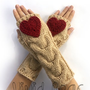 May include: Beige cable-knit fingerless gloves with a red heart appliqué on each. The gloves are made of a soft yarn and feature a ribbed cuff. The text "Vivid Bear" is at the bottom.