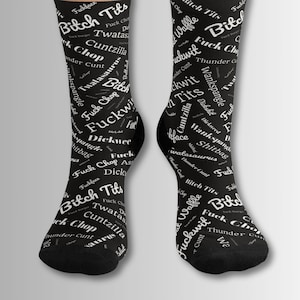 May include: A pair of black socks with a white print of various words, including "Bitch Tits", "Fuck Chop", "Twatasa", "Cuntzilla", "Dickwee", "Wankspangle", and "Thunder Cunt".