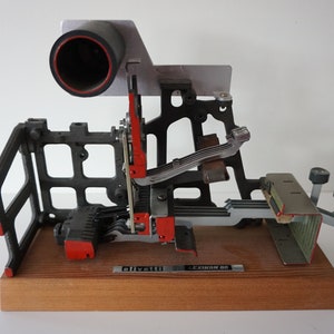 Peut inclure: Gros plan d'une machine à écrire mécanique vintage Olivetti Lettronica 60. La machine à écrire est démontée et exposée sur une base en bois. Le mécanisme est visible, avec des pièces métalliques et des accents rouges. La machine à écrire est étiquetée "Olivetti Lettronica 60".