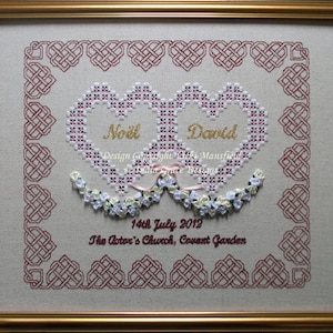 May include: Embroidered wedding sampler with two intertwined hearts, featuring the names "Noll" and "Dovid" in gold thread. The sampler is framed in a gold frame and includes the date "14th July 2012" and the location "The Actor's Church, Covent Garden".