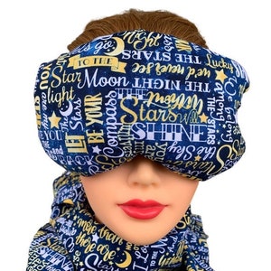 May include: A blue sleep mask with a white and gold print of stars, moons, and words like "Let Be Your Compass" and "Shine" on a dark blue background.