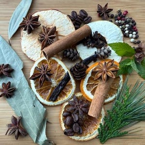 May include: Overhead shot of various spices and dried fruits on a wooden surface. Includes star anise, cinnamon sticks, dried orange slices, coffee beans, peppercorns, and bay leaves. Aromatic ingredients for cooking or crafts.