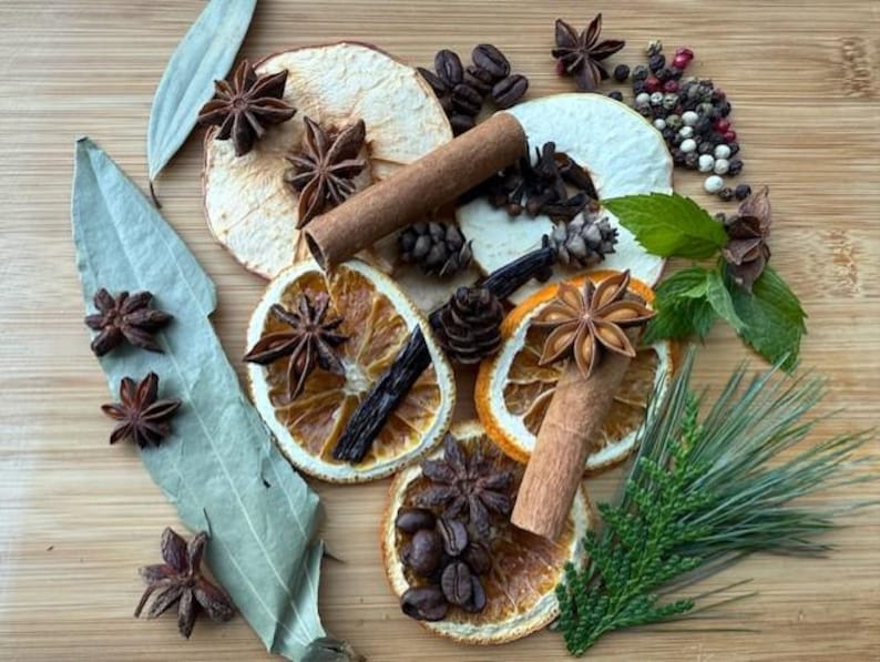 May include: Overhead shot of various spices and dried fruits on a wooden surface. Includes star anise, cinnamon sticks, dried orange slices, coffee beans, peppercorns, and bay leaves. Aromatic ingredients for cooking or crafts.