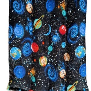 May include: A rectangular, black fabric item with a colorful space-themed pattern. The design features planets, galaxies, stars, and moons in shades of blue, orange, red, and yellow. The item appears to be a heating pad or pillow.