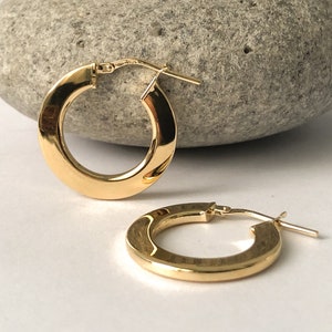 May include: A pair of gold hoop earrings. The earrings are simple and elegant, with a smooth, polished finish.