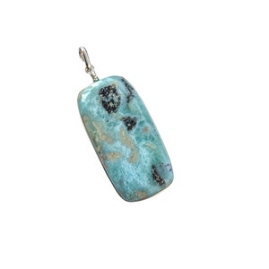 May include: A pendant featuring a light blue and white seafoam jasper stone with black inclusions, set in silver.