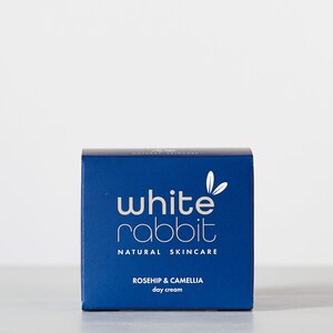 K&ouml;nnte beinhalten: Eine blaue Box mit wei&szlig;em Text, auf der "white rabbit natural skincare rosehip & camellia day cream" steht.