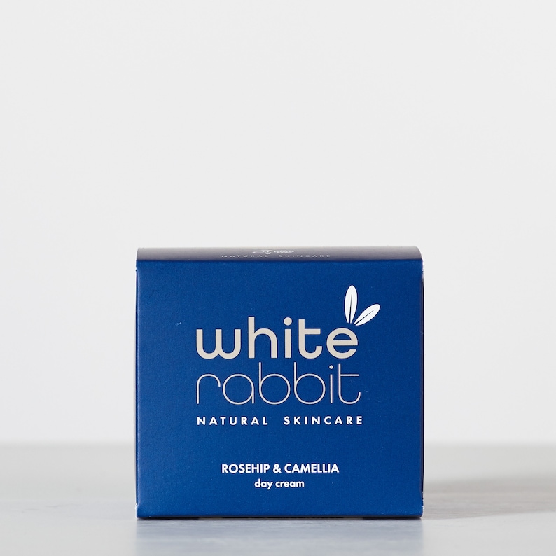 K&ouml;nnte beinhalten: Eine blaue Box mit wei&szlig;em Text, auf der "white rabbit natural skincare rosehip & camellia day cream" steht.