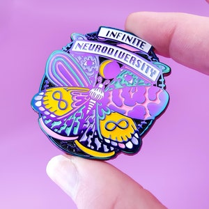 Peut inclure: Une épingle en émail noir avec un motif de papillon coloré. Le papillon a des ailes jaunes, roses, bleues et vertes. L'épingle indique "Neurodiversité Infinie" en lettres blanches.