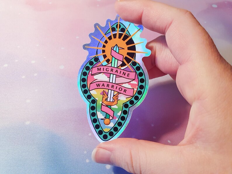 Pu&ograve; includere: Un adesivo olografico con un design arcobaleno che presenta una spada, un sole e nuvole. Il testo "Migraine Warrior" &egrave; scritto su uno stendardo rosa.