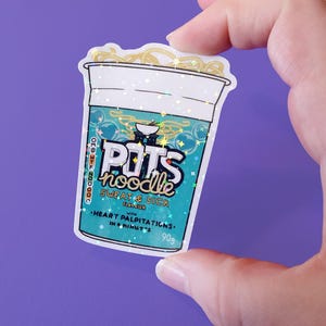 May include: A sticker of a blue and white instant noodle cup with the text "POTS noodle SWEAT & SICK" and "HEART PALPITATIONS. IN 4 MINUTES. 90g". The sticker has a glittery finish.