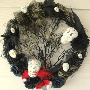 May include: A black and gold Day of the Dead wreath with a variety of colorful sugar skulls, black flowers, and black and gold spiderwebs.