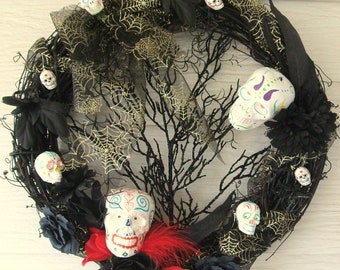 May include: A black and gold Day of the Dead wreath with a variety of colorful sugar skulls, black flowers, and black and gold spiderwebs.