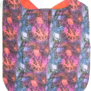 May include: A colorful bib with a marbled pattern in shades of pink, blue, and black. The bib has a red fabric lining around the neck.