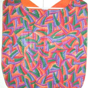 May include: A colorful bib with a geometric pattern in shades of orange, red, green, purple, and blue. The bib is made of a soft, comfortable fabric and has a simple design.