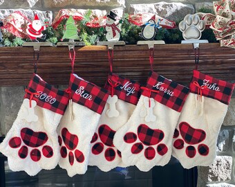 May include: Five red and black plaid Christmas stockings with white paw prints and personalized names: Coco, Star, Neji, Korra, and Zuko.