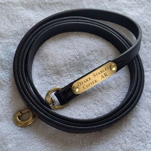 May include: Black leather dog leash with a brass tag that reads "Ozark Stables Cotter, AR".