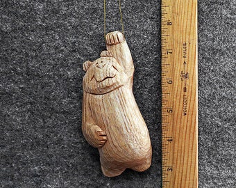 Hang in there bear ornament.  This artist created 5 inch original bear ornament has been hand carved from the wood of the Butternut tree.