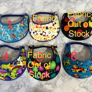 May include: Six sun visors with different colorful patterns. The visors are numbered 1 through 6. Visors 2, 3, and 5 are marked "Fabric Out of Stock".