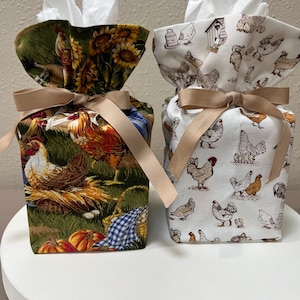 May include: Two fabric tissue box covers with a gathered top and a beige ribbon bow. The left cover features a colorful farm scene with chickens, sunflowers, and pumpkins. The right cover has a white background with a repeating pattern of chickens.