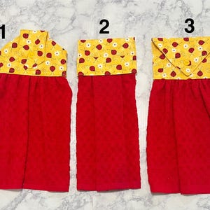 May include: Three red kitchen towels with a yellow top featuring a ladybug and flower pattern. The towels are made of a textured fabric. Each towel has a different top design, including a button closure and a folded design.