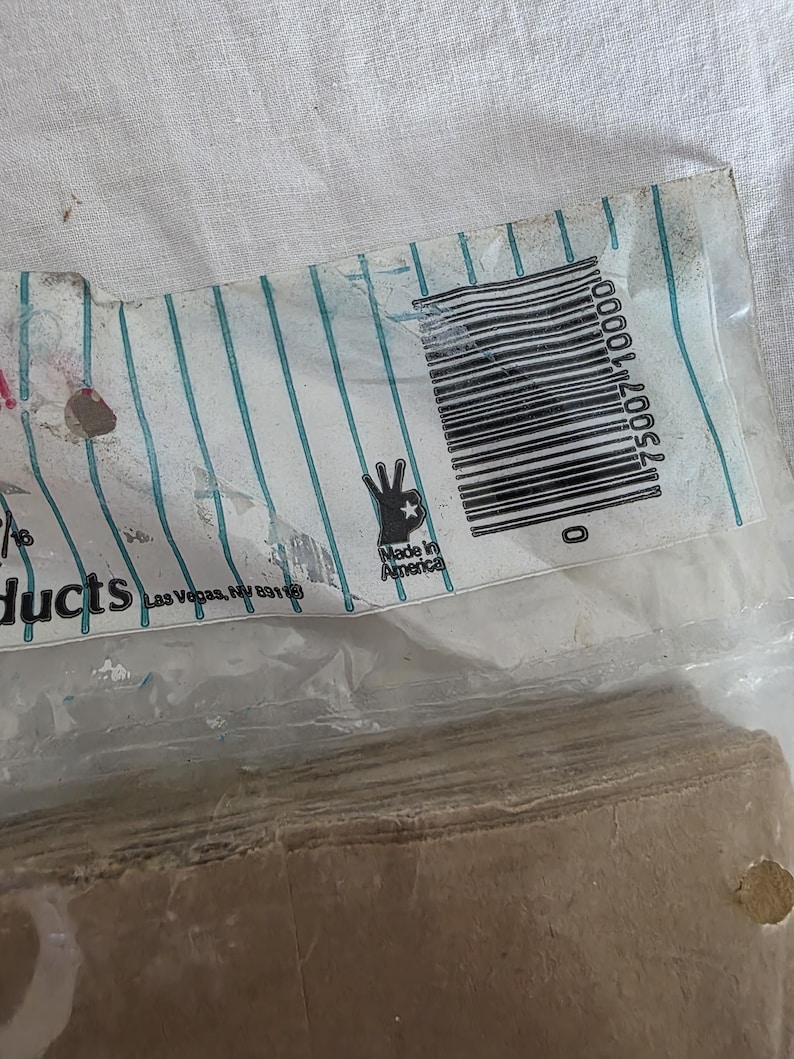 May include: A partially visible package with a barcode and the text "Made in America". The packaging has a white background with teal vertical stripes. The bottom portion of the package contains a stack of brown paper.