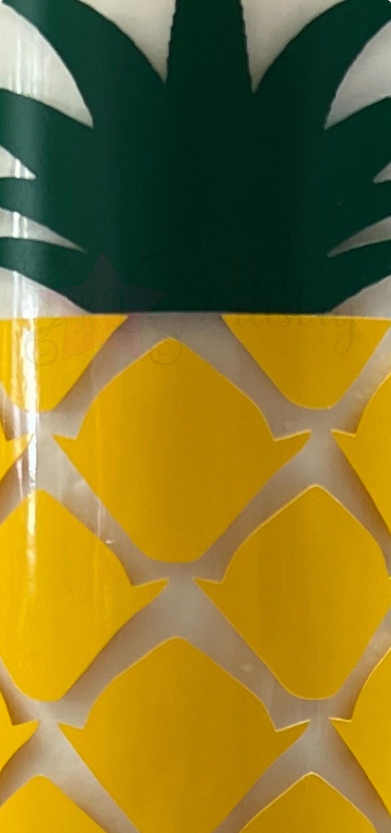 May include: A yellow pineapple-shaped tumbler with a green pineapple top. The tumbler has a white background with a yellow pineapple pattern.