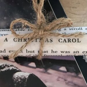 May include: A rolled up book tied with twine, the cover reads "A Christmas Carol".