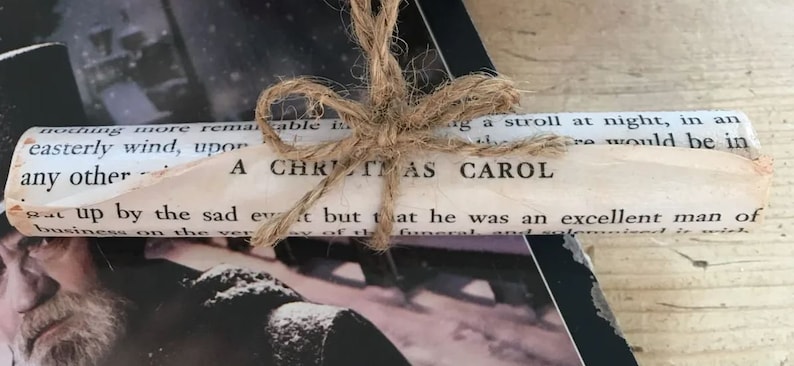 May include: A rolled up book tied with twine, the cover reads "A Christmas Carol".