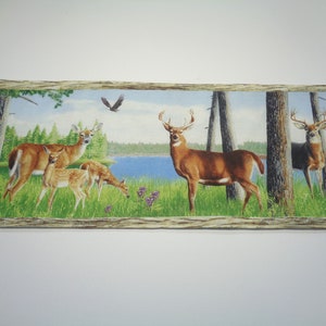 May include: A colourful fabric panel depicting a woodland scene with a buck, doe, and two fawns in a forest setting. The panel features a blue lake in the background and a brown wooden frame.