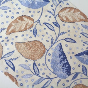 May include: A white fabric with a blue and brown leaf pattern. The leaves are stylised and have a delicate, intricate design.