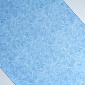 May include: A rectangular fabric piece featuring a light blue background with a white, rippling water surface pattern. The design mimics the appearance of sunlight reflecting on the bottom of a swimming pool with soft, interconnected lines.